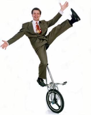 Man wearing a suit and standing on a unicycle