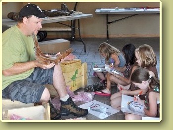 Man showing dinosaur bone to children