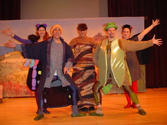 Five people with arms raised, dressed as insects.
