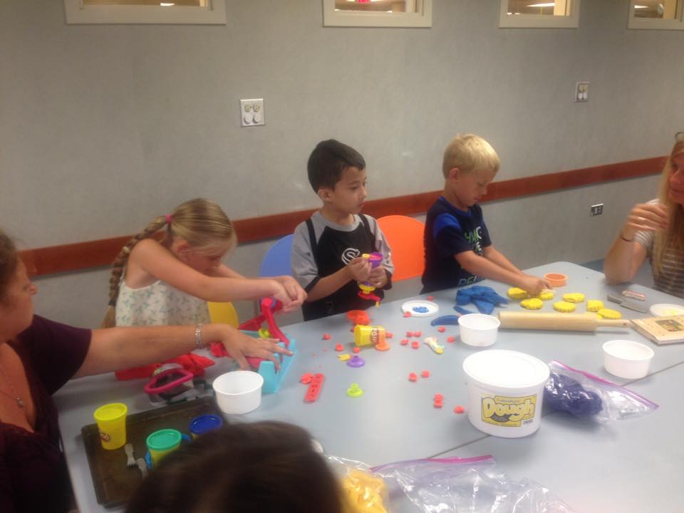 Three children playing with play dough.