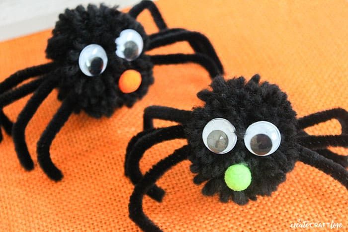 Two spiders made out of yarn pom poms with wiggly eyes.