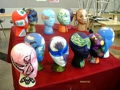 A table containing several painted styrofoam heads
