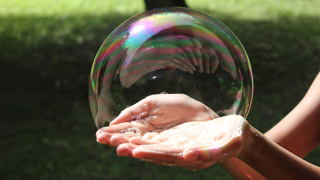 A large soap bubble being held in a person's hands.