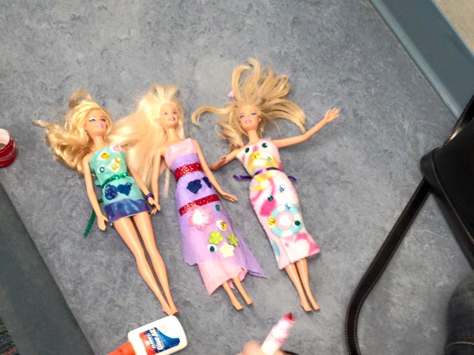Three Barbies in paper dresses.