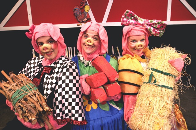 Three adults in pig costumes.