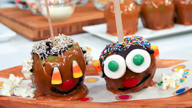 Two carmel apples with candy faces.
