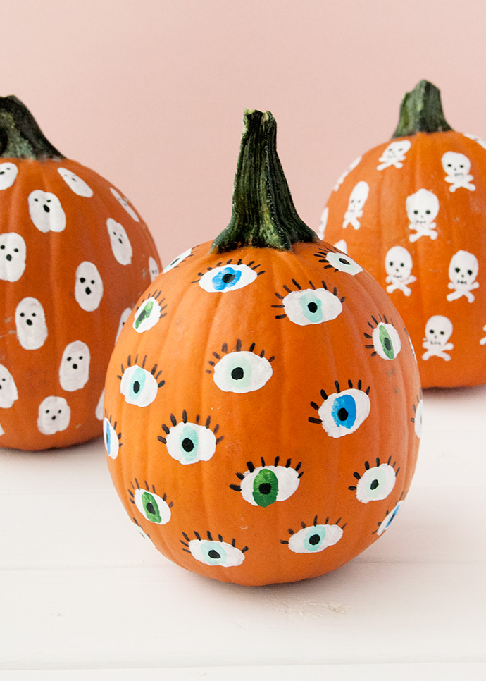 Three pumpkins.  One with many eyes painted on it.  One with many ghosts and one with many skulls.