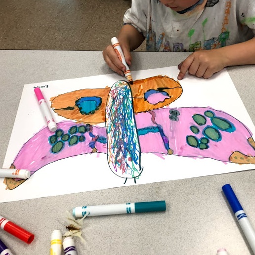Child drawing a large butterfly with markers