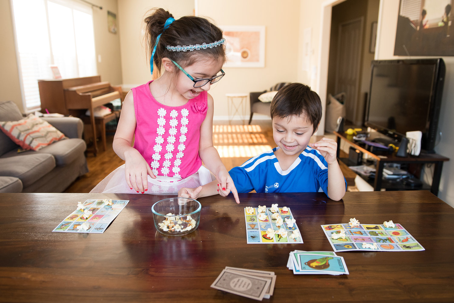 Two smiling children playing Loteria, a bingo game from Mexico.