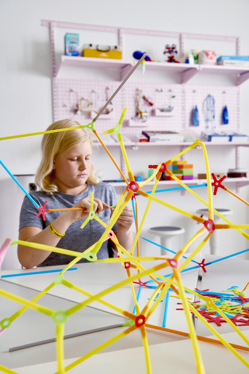 A girl building with a construction toy.