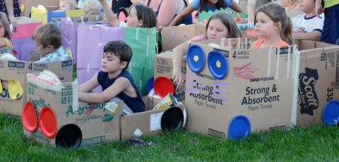 Children sitting in cardboard boxes decorated like cars.