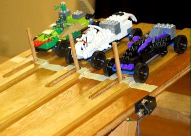 Lego cars on a wooden track.