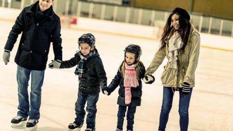 A family ice skating and holding hands in a row.
