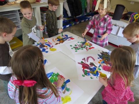 Four children painting around a table.