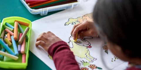 Child coloring a picture of a sheep.