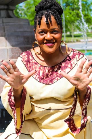 Woman in a flowing dress holding her hands out in front of her.