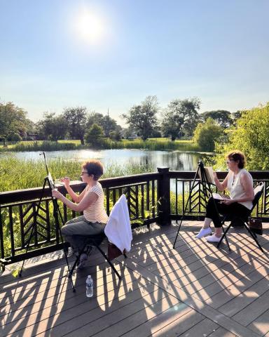 People outside painting by a pond