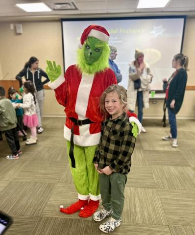 A person in a Grinch costume with their hand on the shoulder of a boy.