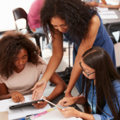 Teacher helping students use technology.