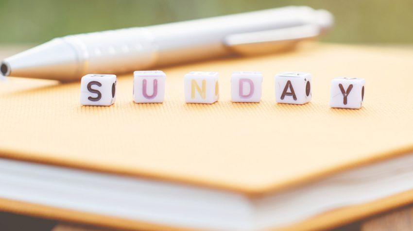 Beads that spell out Sunday, on top of a book.