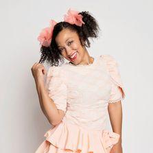 Woman with curly, dark hair and pigtails in a frilly dress.