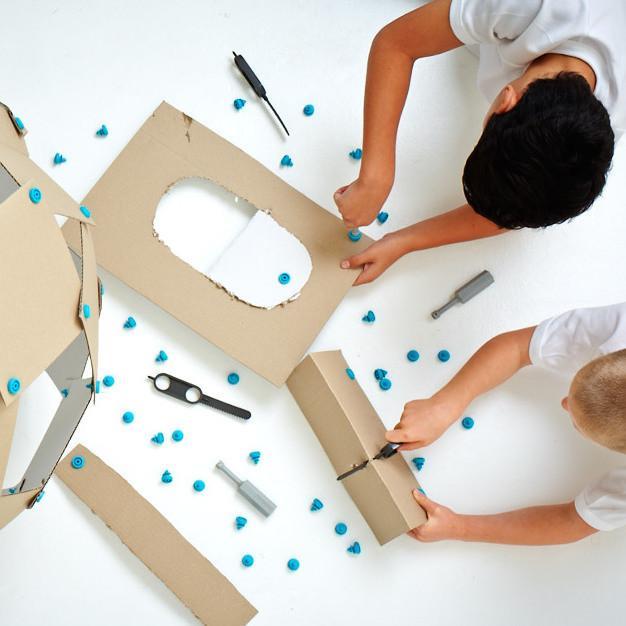 Two boys sawing pieces of cardboard