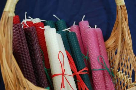 About a dozen rolled beeswax candles in a basket.