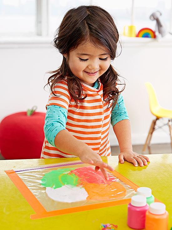 Little girl pressing paint in a plastic bag.