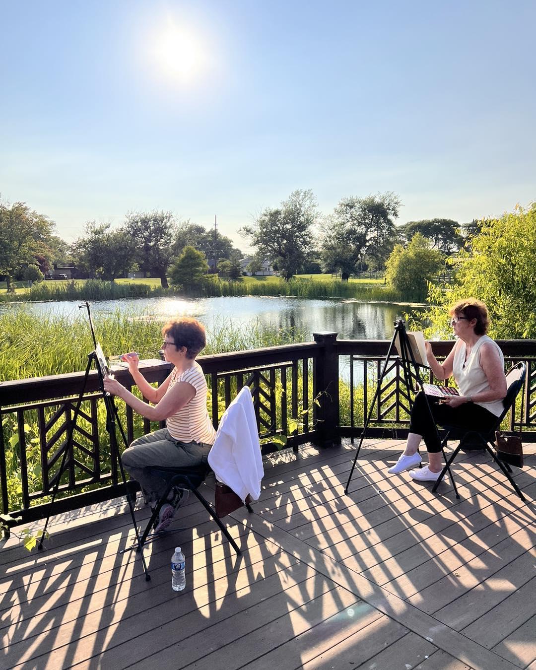People outside painting by a pond